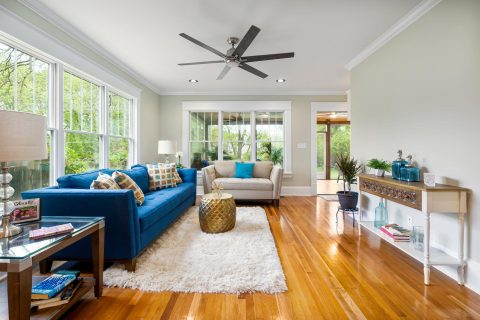 A living room with hardwood floors and a ceiling fan that receives rave reviews.