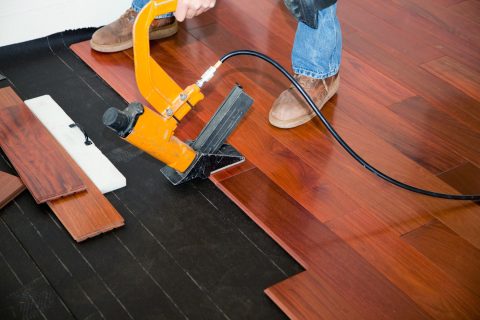Hardwood Flooring 8 A man is using a tool to install hardwood flooring.