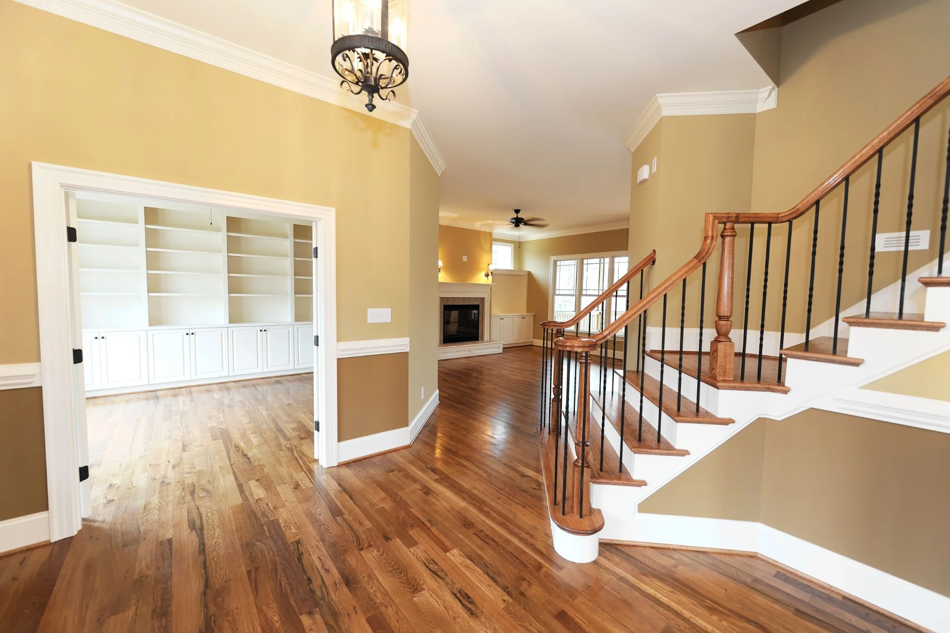 A hallway with hardwood flooring and a staircase.