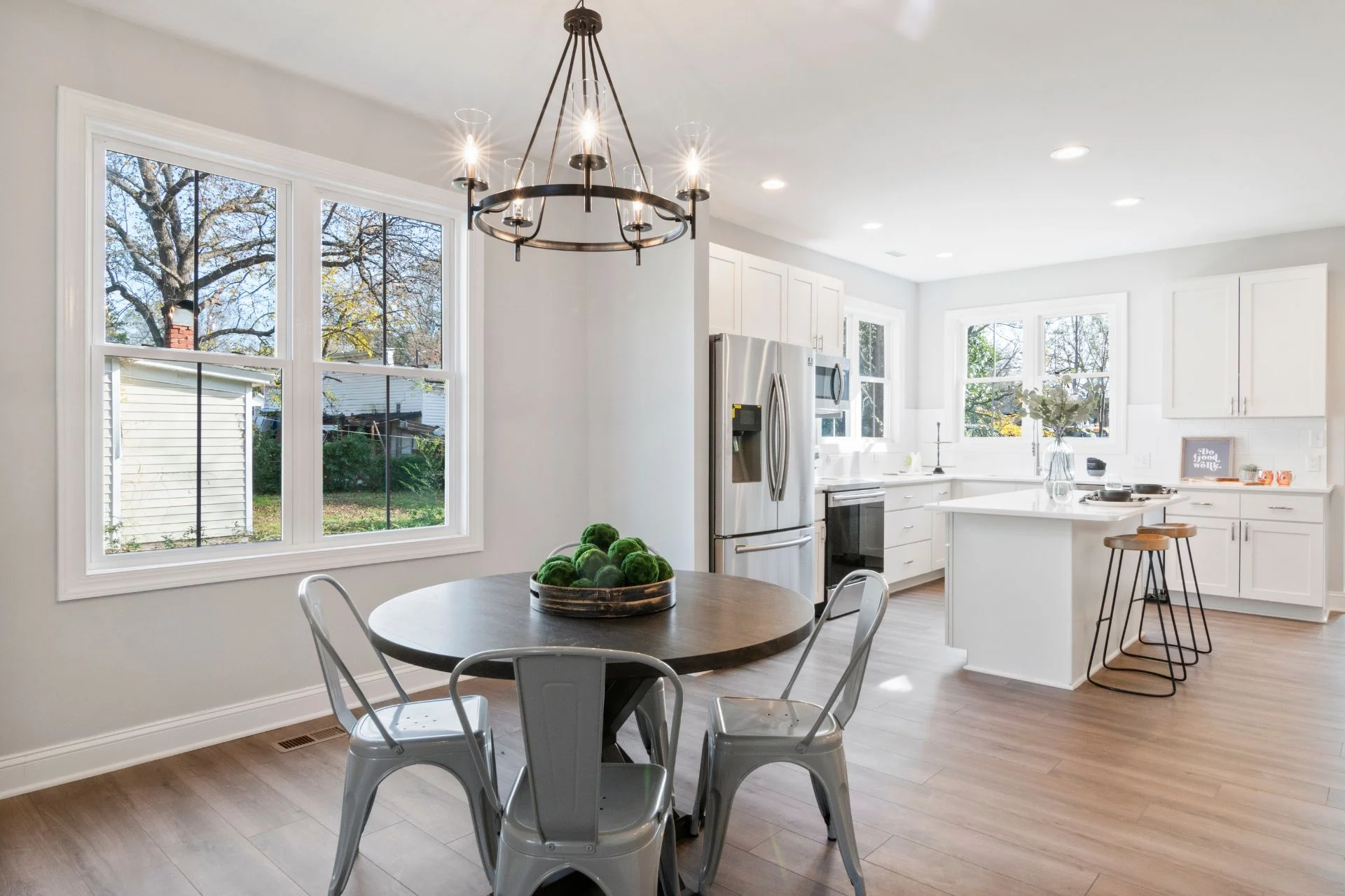 A white kitchen with hardwood flooring and a dining table.