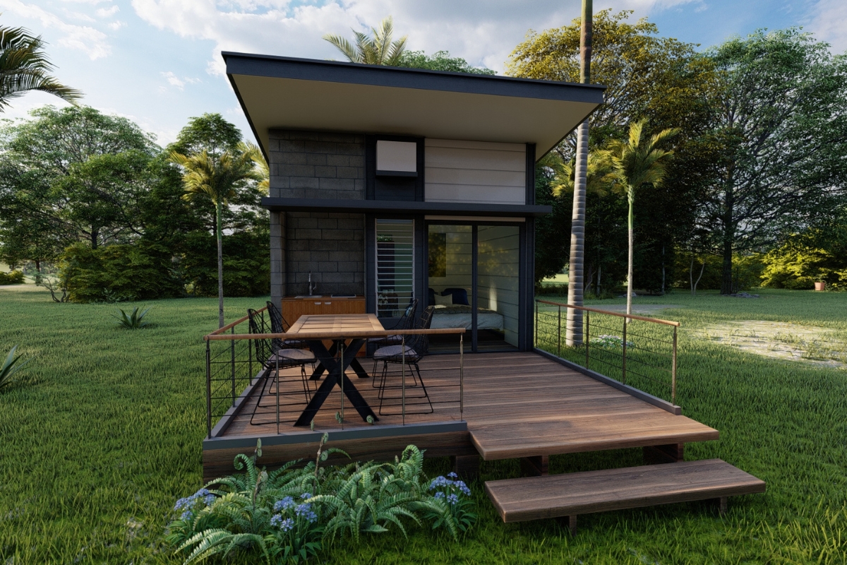 A tiny house with a deck, embracing the tiny home trend, nestled in the middle of a grassy area.