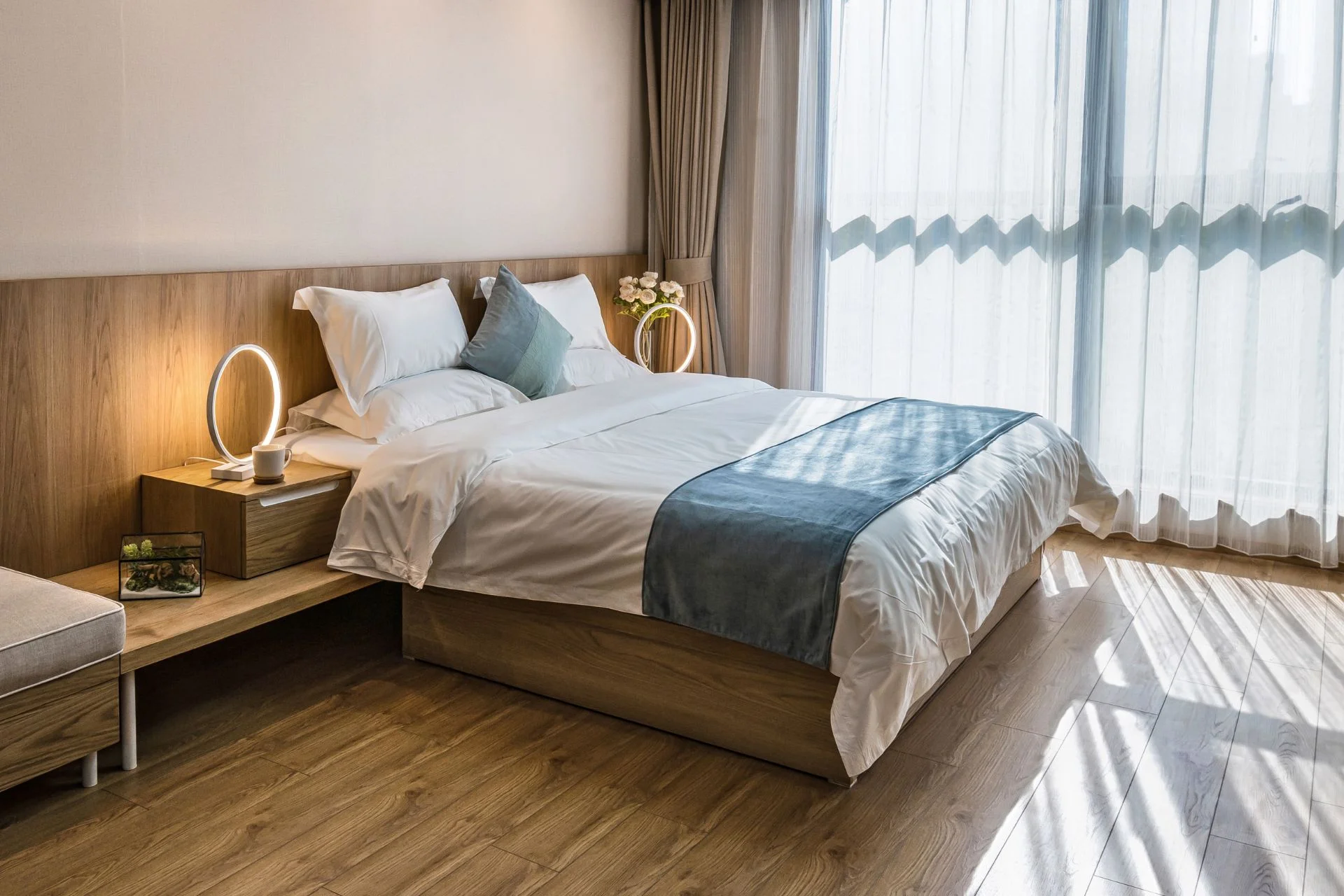 A bed in a room with vinyl flooring and a window.