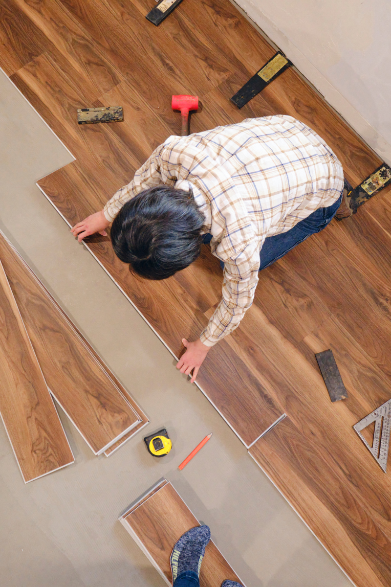 Canton Flooring Services 9 A man is installing wood flooring in a room for Canton Flooring Company.