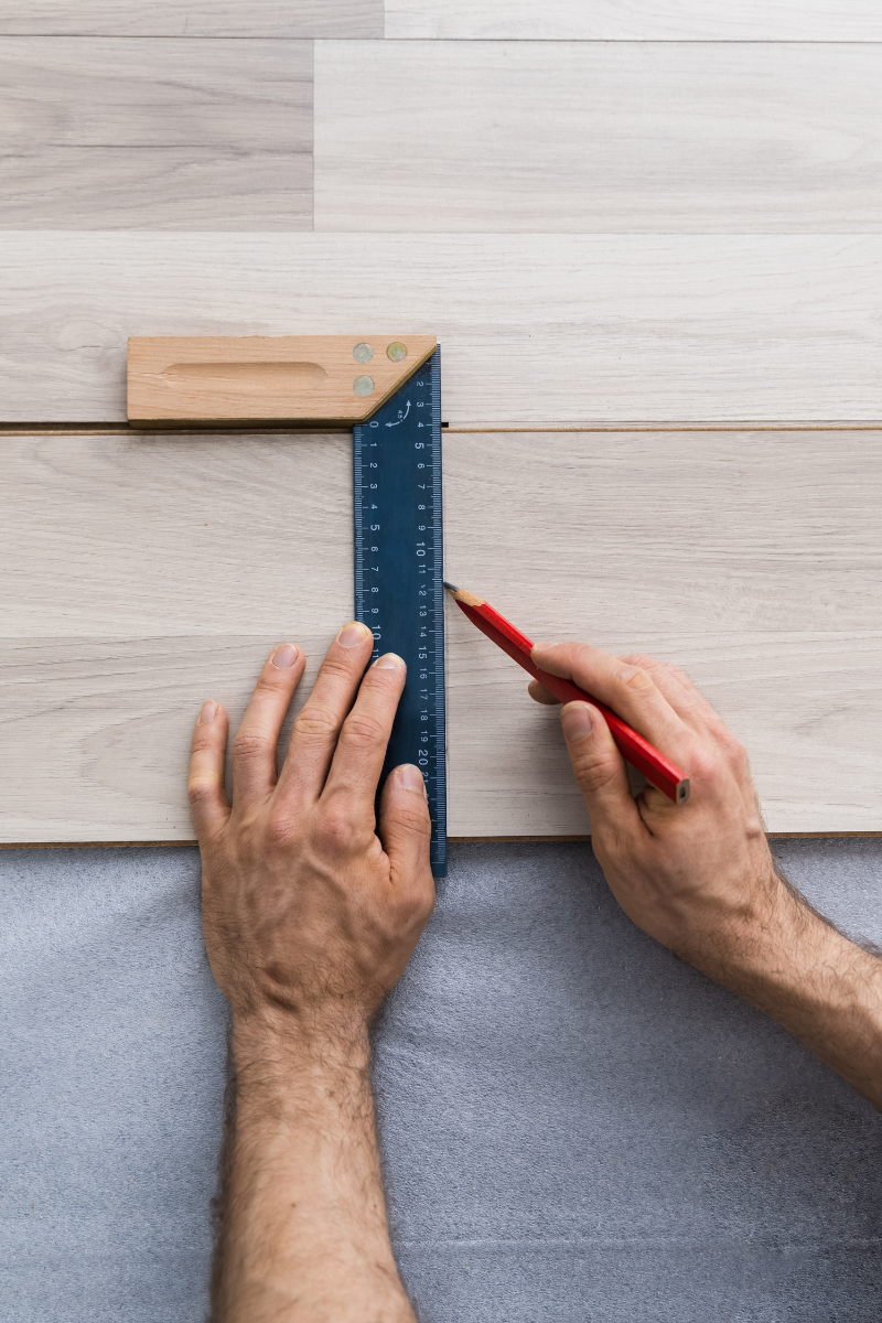 Cartersville Flooring Services 9 A man from Cartersville Flooring Company using a ruler to measure a wooden floor.