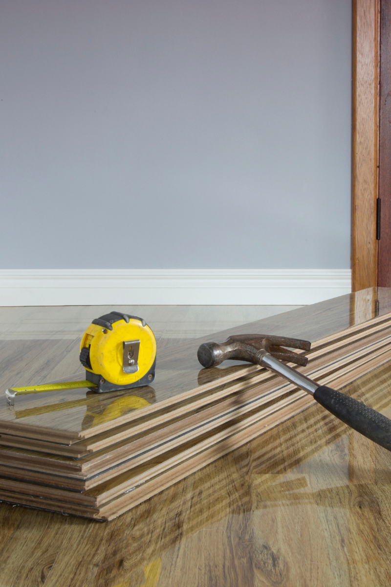 College Park Flooring Company 10 A hammer and a tape measure on a College Park wooden floor.