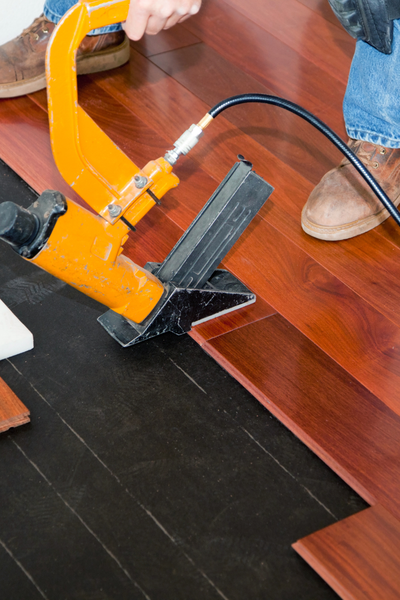A Dallas flooring company using a tool on a wooden floor.