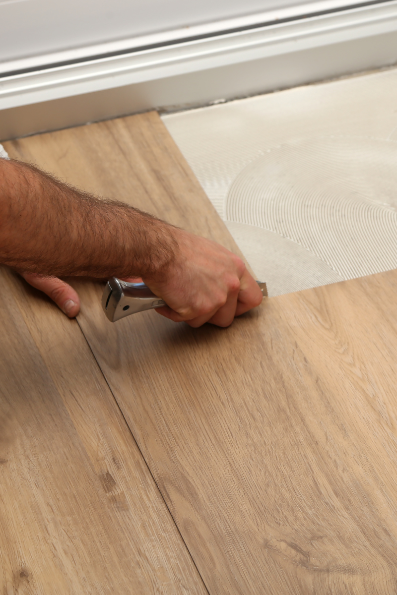 Brookhaven Flooring Services 9 A man is installing wood flooring for Brookhaven Flooring Company.