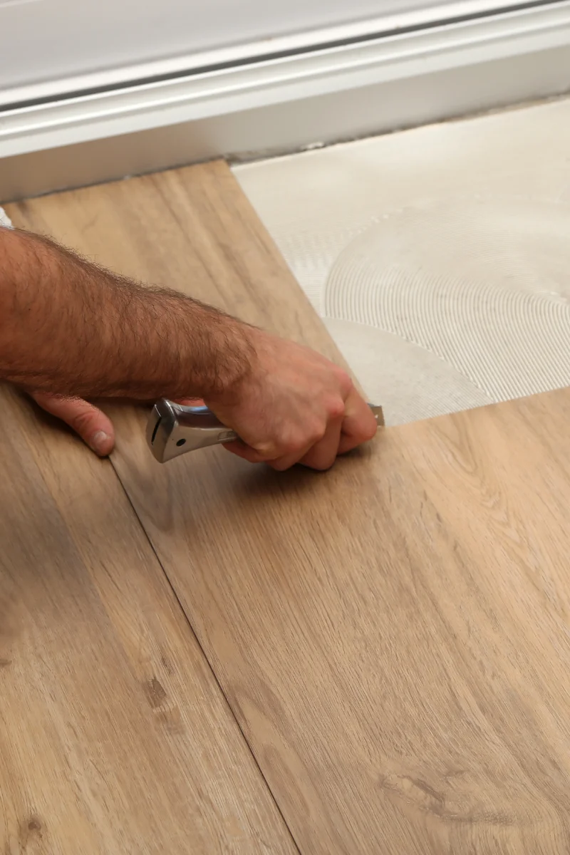 Brookhaven Flooring Services 29 A man is installing wood flooring for Brookhaven Flooring Company.