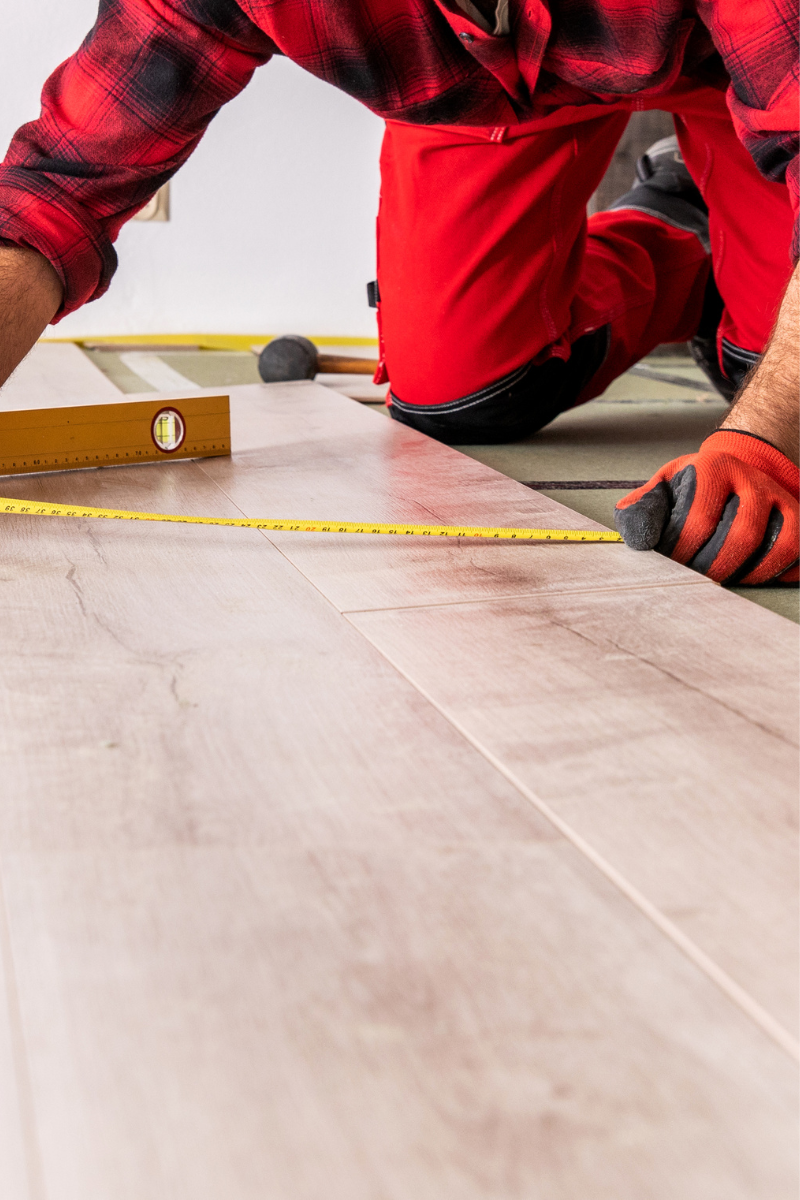 Brookhaven Flooring Services 10 A man measuring the length of a wooden floor for Brookhaven Flooring Company.