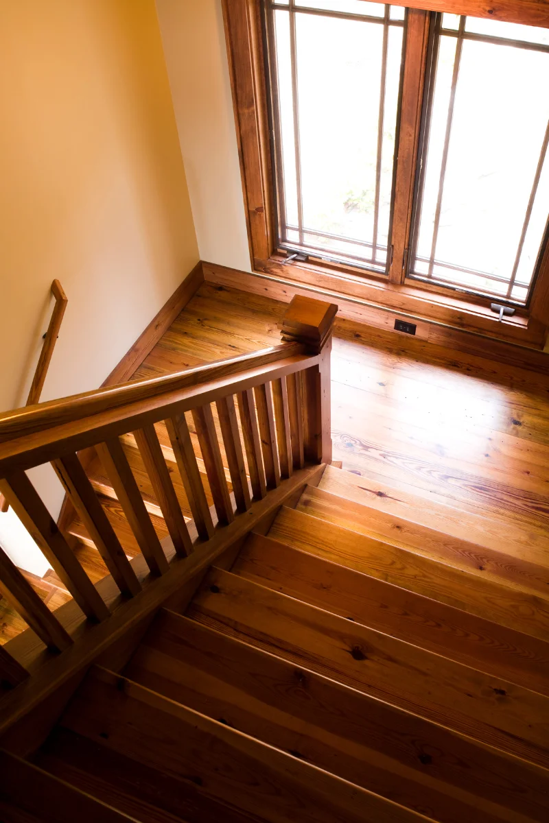 A wooden staircase with Chamblee Flooring Company's wooden railings and a window.