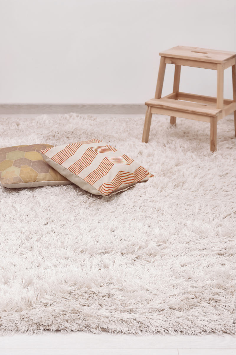 A white rug with pillows and a stool, perfect for the Douglasville Flooring Company.