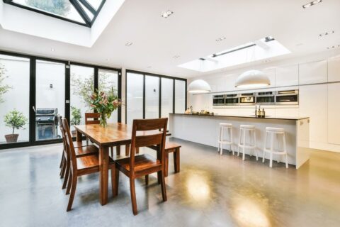 A modern kitchen with a skylight and furniture combinations over the dining table.