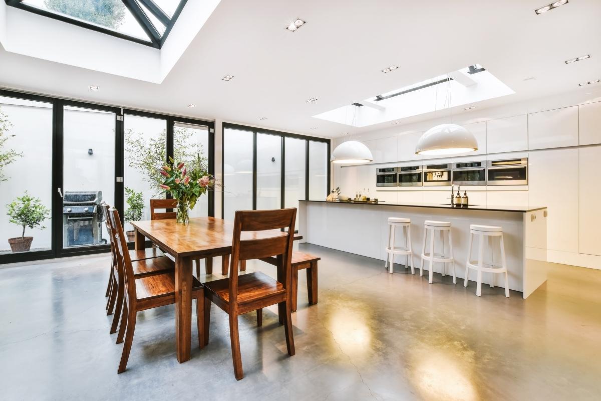 A modern kitchen with a skylight and furniture combinations over the dining table.