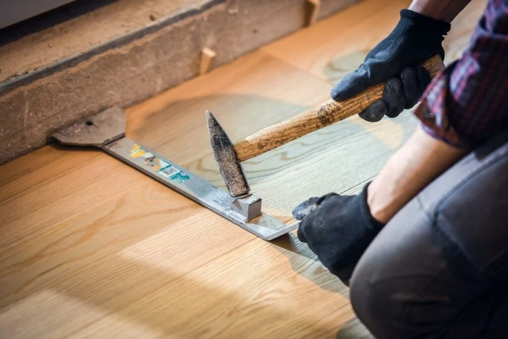 A man is installing hardwood flooring.