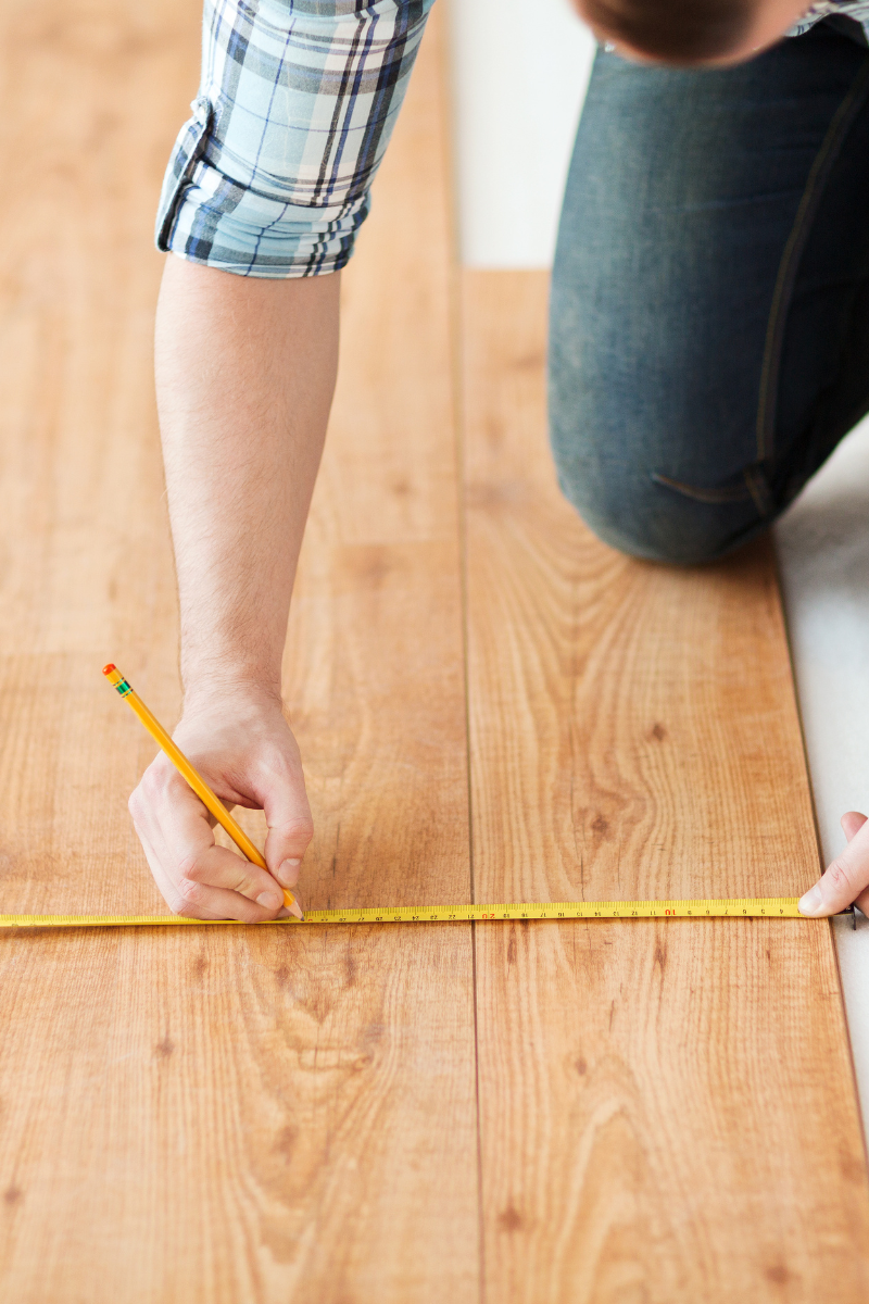 A man measuring a wooden floor for installation.