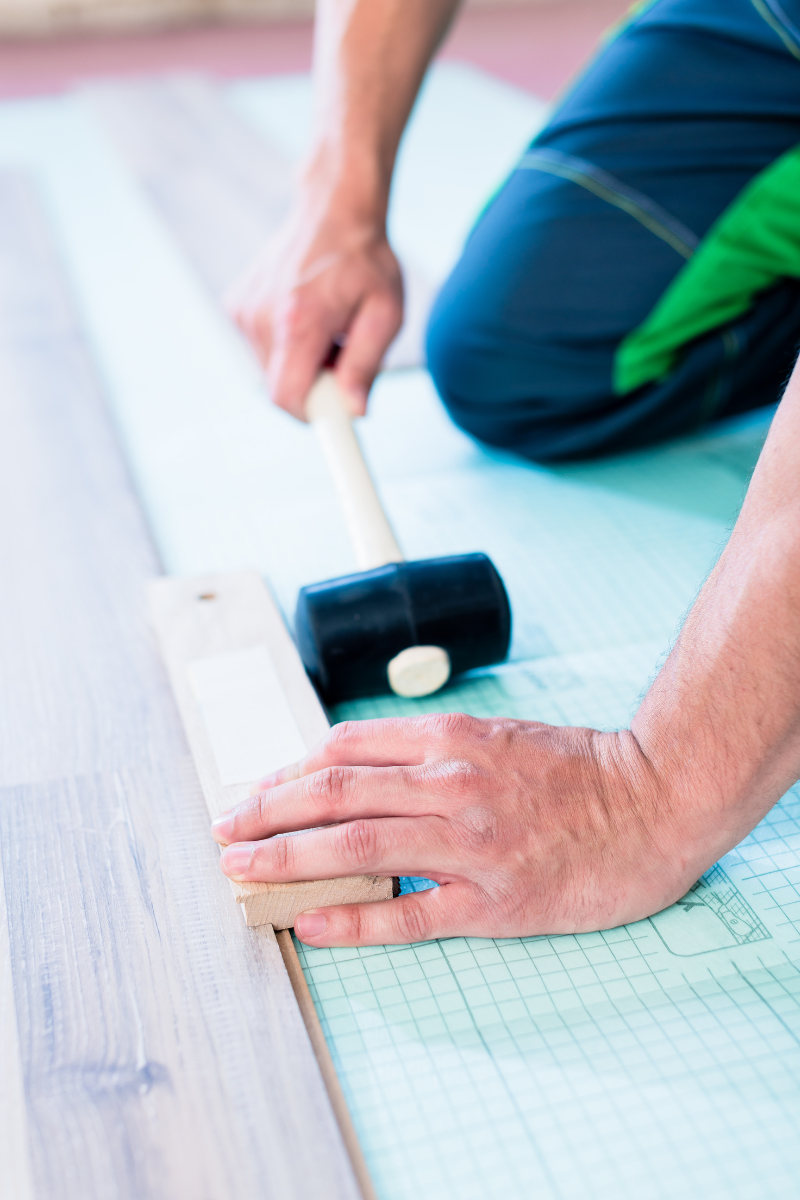 Kennesaw Flooring Services 10 A man from Kennesaw Flooring Company is hammering a wooden floor.