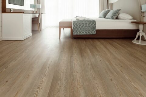 A bedroom with engineered hardwood flooring and a bed.