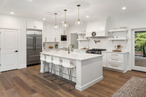 Blog 1 A white kitchen with hardwood floors and a center island, perfect for those who love the warmth and elegance of hardwood flooring in kitchens.