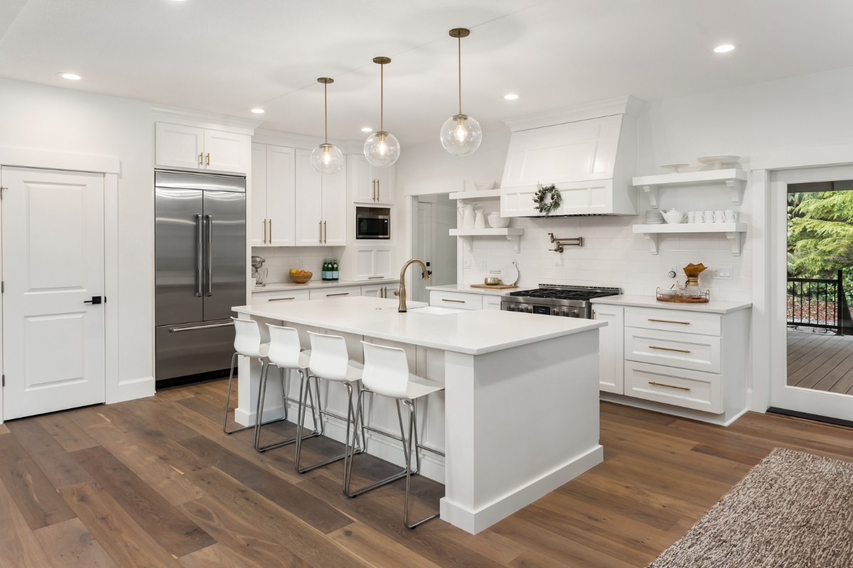 A white kitchen with hardwood floors and a center island, perfect for those who love the warmth and elegance of hardwood flooring in kitchens.