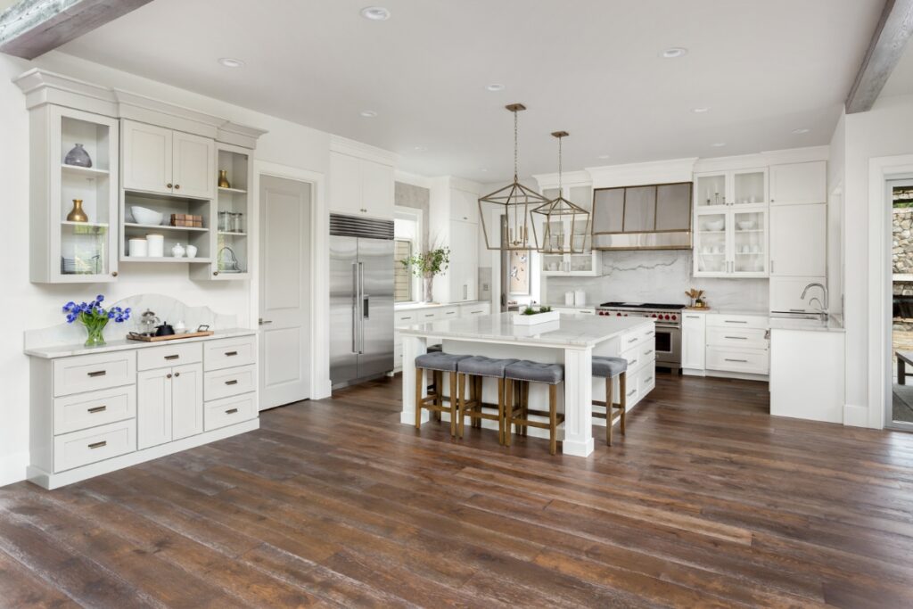 The Pros and Cons of Hardwood Flooring in Kitchens 2 A white kitchen with hardwood floors and a center island.