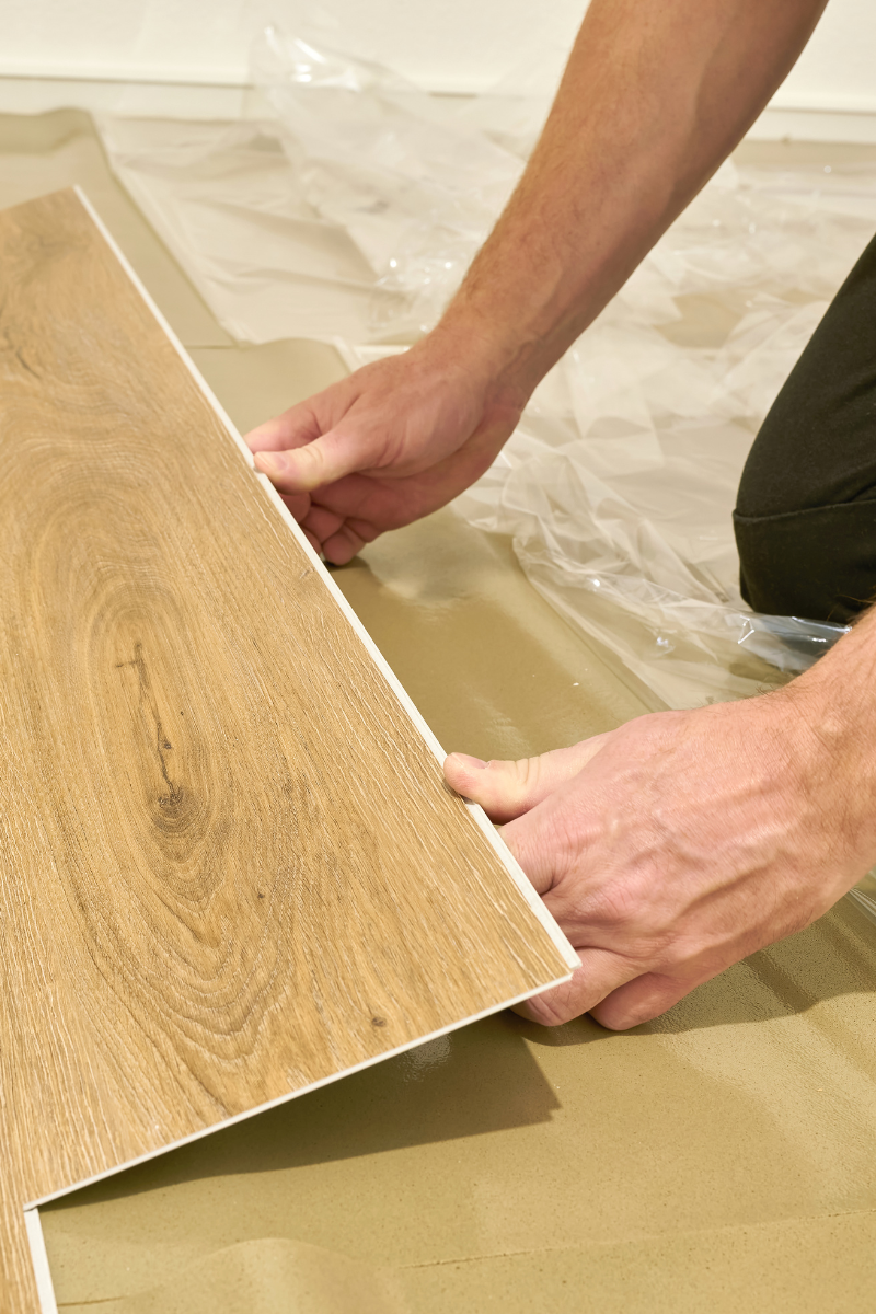 Lawrenceville Flooring Company 9 A skilled technician is meticulously laying down wood flooring on a floor.
