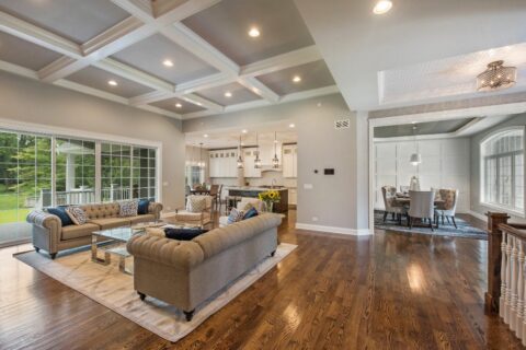 Open-plan living area with a kitchen, dining, and living room, featuring coffered ceilings, large windows, and hardwood floors from the best flooring brands.