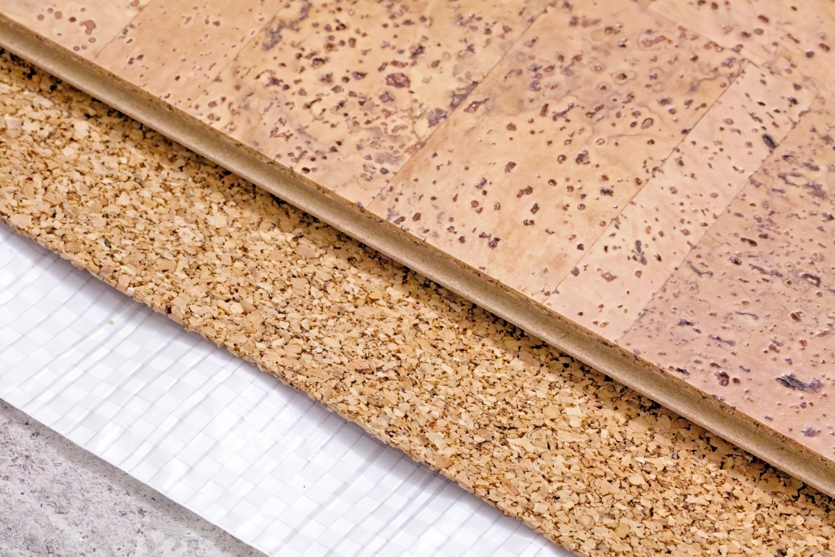 Blog 1 Close-up of a layered cork board, showing a polished top layer and a rough, granulated lower layer, placed on a white grid surface—showcasing innovative floor technologies.