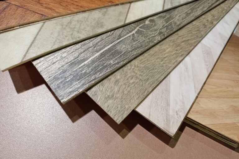 A fan spread of wood-patterned laminated floor tiles in various shades, showcasing healthy flooring options, displayed on a flat surface.