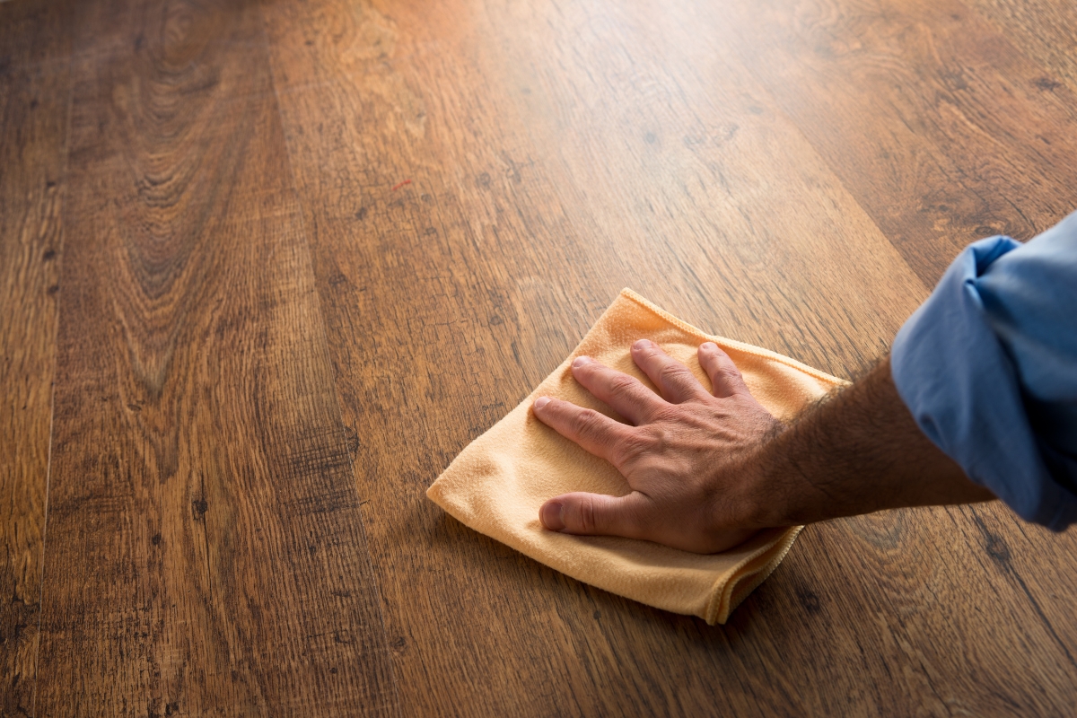 Scratch-Resistant Hardwood Floors for Cartersville Homes: Tips to Prevent Damage 4 A person wipes a wooden surface with a yellow cloth, keeping their scratch-resistant hardwood floors looking spotless.