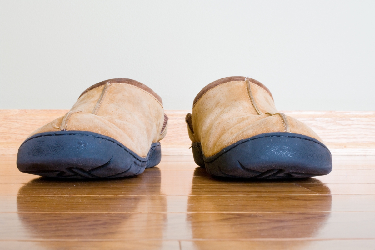Scratch-Resistant Hardwood Floors for Cartersville Homes: Tips to Prevent Damage 8 A pair of worn tan slippers with dark soles sits side by side on scratch-resistant hardwood floors against a plain light-colored wall.