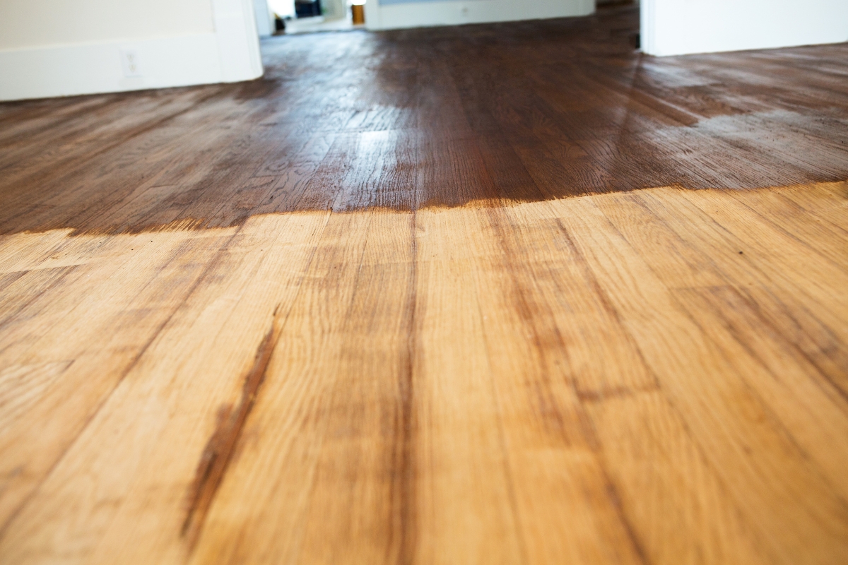 Wood Floor Refinishing in Brookhaven: Key Signs It's Time to Refinish Your Floors 6 Partially stained wood floor highlights the striking contrast between the finished darker side and the unfinished lighter side in a room.