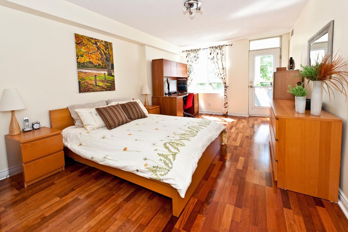 Best Flooring Options for High-Traffic Areas in Chamblee Homes 5 A tidy bedroom with a wooden bed, nightstands, dresser, desk, computer, and a window with patterned curtains letting in natural light—highlighting some of the best flooring options for a cozy, organized space.