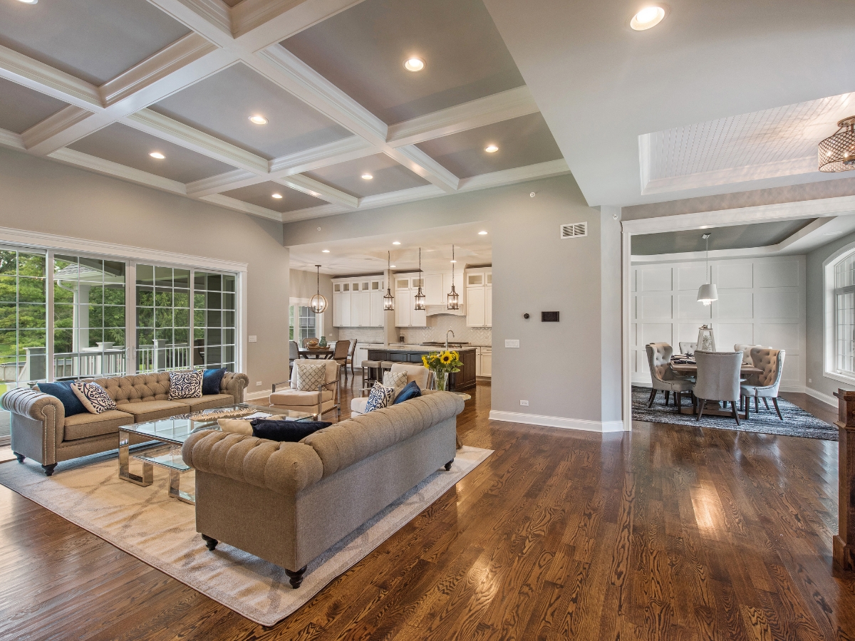 Engineered Hardwood vs. Solid Hardwood: Which is Better for Dallas Homes? 14 Spacious open-concept living area with engineered hardwood floors, two sofas, a glass coffee table, and a view into the kitchen and dining room. Large windows provide abundant natural light.