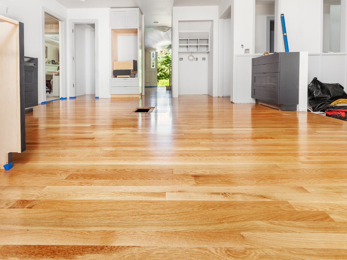 How to Restore Hardwood Floors in Older Decatur Homes Without Damaging Them 8 A room with newly installed light wood flooring, unfinished cabinetry, and construction materials, showcasing ongoing home renovation and efforts to restore hardwood floors.