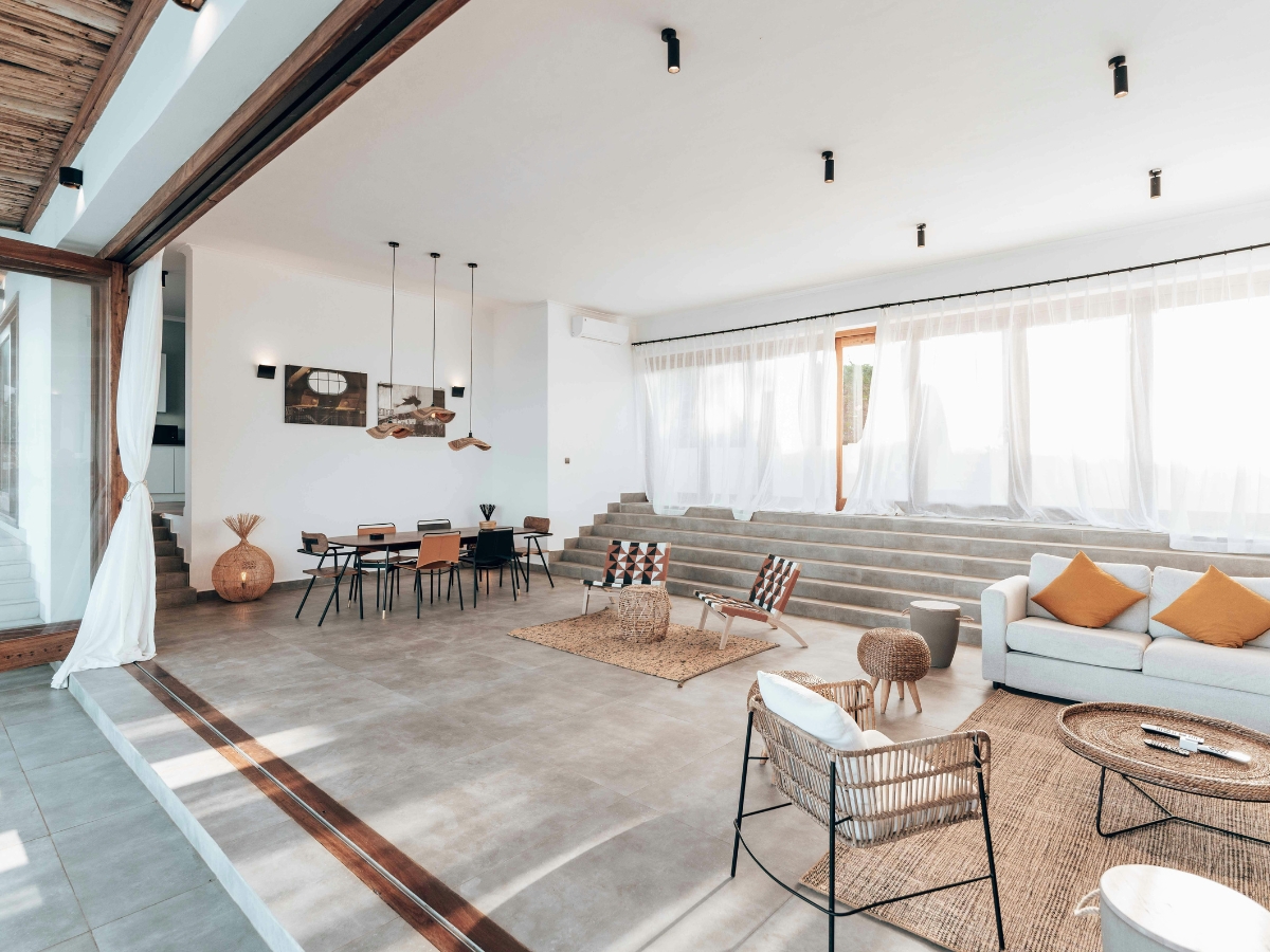 Top Flooring Options for Open-Concept Homes in Lithia Springs, GA 1 Spacious modern living and dining area with large windows, neutral-toned furniture, light curtains, and tiered steps—showcasing one of the top flooring options for open-concept homes in Lithia Springs.