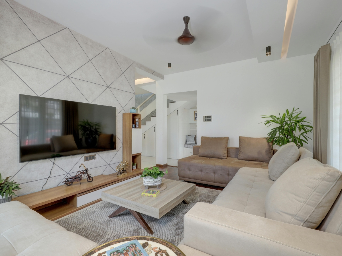 Modern living room designed for small spaces, featuring neutral-toned sofas, a geometric accent wall, flat-screen TV, potted plants, and a wooden coffee table arranged on a gray rug.