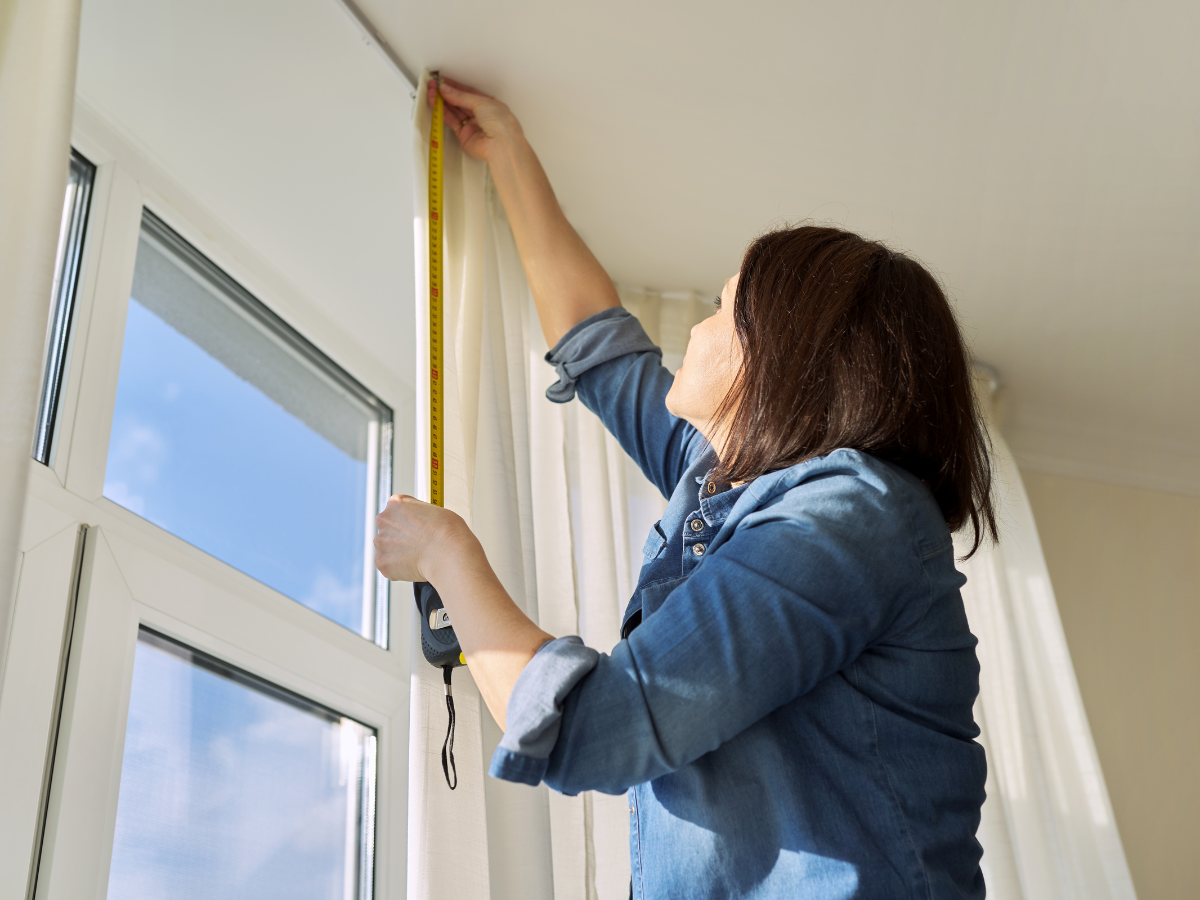 A Room Measurement Guide: Basics for Better Flooring Estimates 1 A person in a denim shirt uses a measuring tape as a measurement guide to determine the height of a window while standing indoors.