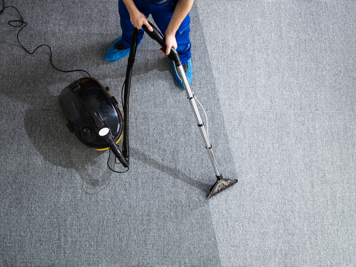 Expert Tips for Carpet Cleaning & Care: Effective Cleaning and Maintenance Strategies 2 A person is using a carpet cleaning machine, demonstrating the effectiveness of carpet cleaning by showing a clear contrast between the cleaned and uncleaned sections of gray carpet.