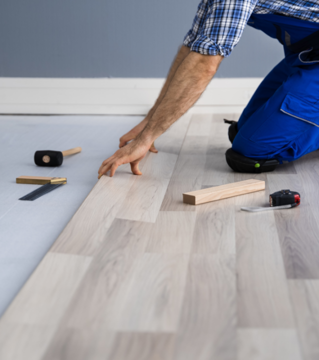 A man from Buckhead Flooring Company is installing wood flooring in a room.