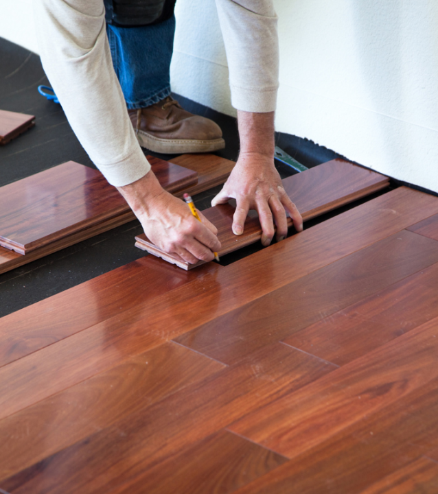 A man from Buford Flooring Company installing hardwood flooring in a room.
