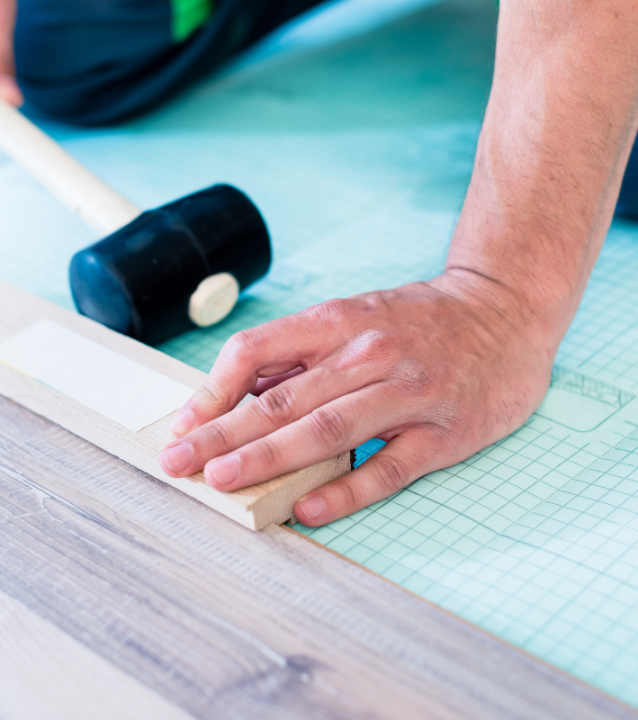 A man is hammering a wooden floor for Carrollton Flooring Company. A man is hammering a wooden floor for Carrollton Flooring Company.