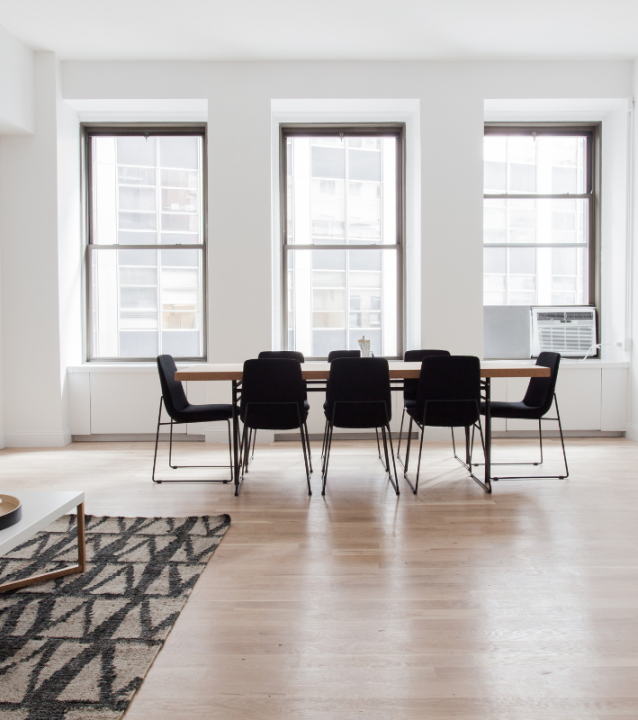 A white living room furnished with a table and chairs, designed by College Park Flooring Company.