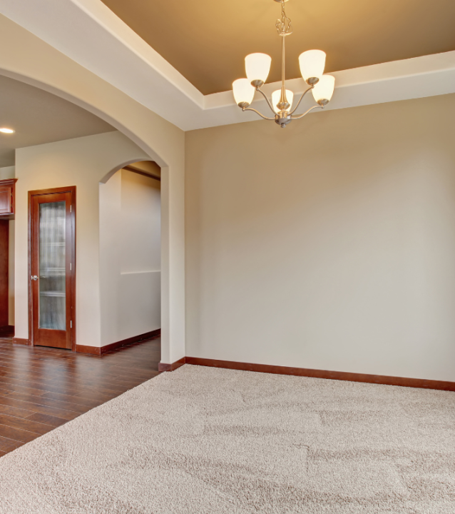 An empty living room with hardwood floors and a kitchen renovated by Decatur Flooring Company.