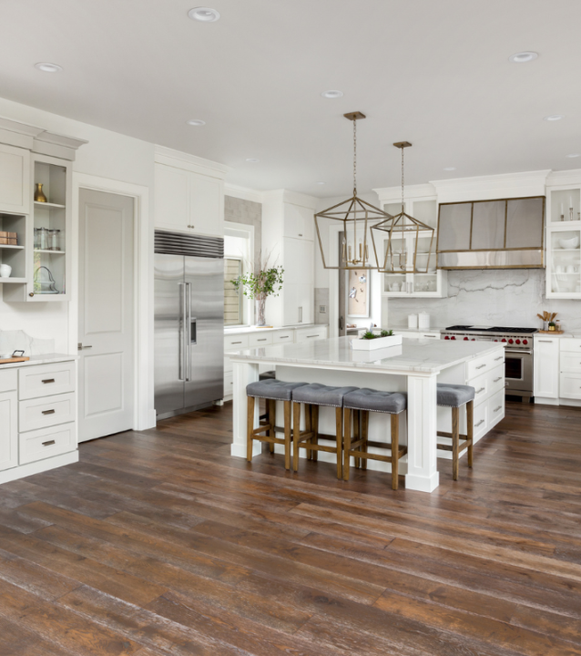 A white kitchen with wood floors provided by Duluth Flooring Company and a center island.