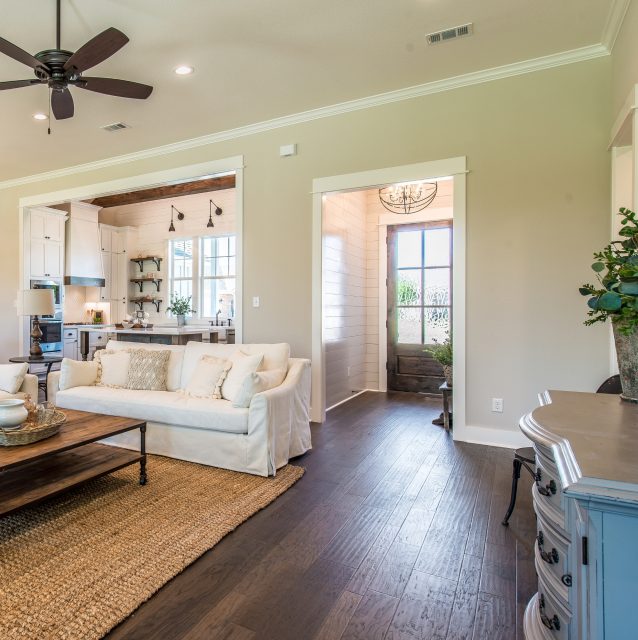 A living room with handscraped hardwood flooring and a ceiling fan.