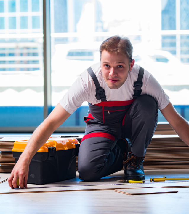 A man in overalls using tools on the floor for Johns Creek Flooring Company.